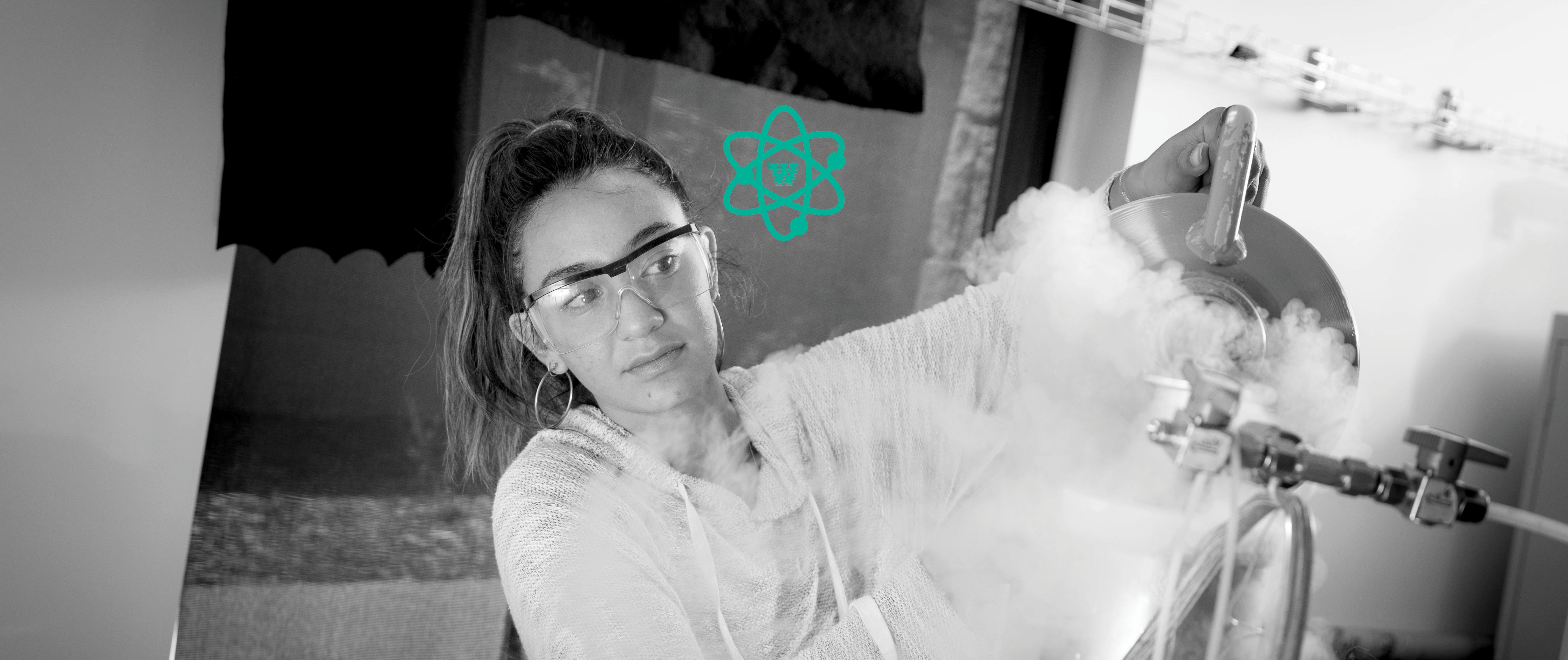 black & white image of female student wearing safety goggles working in lab; Westmont STEM icon above.